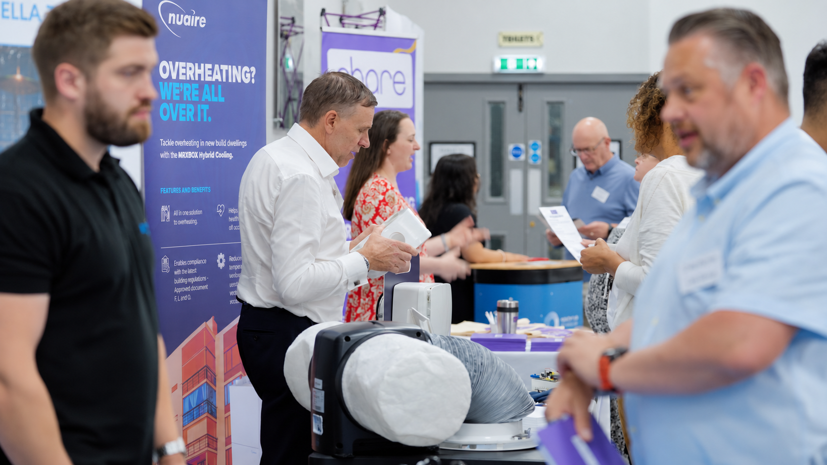 Delegates speaking with exhibitors beside the Nuaire and Share stands