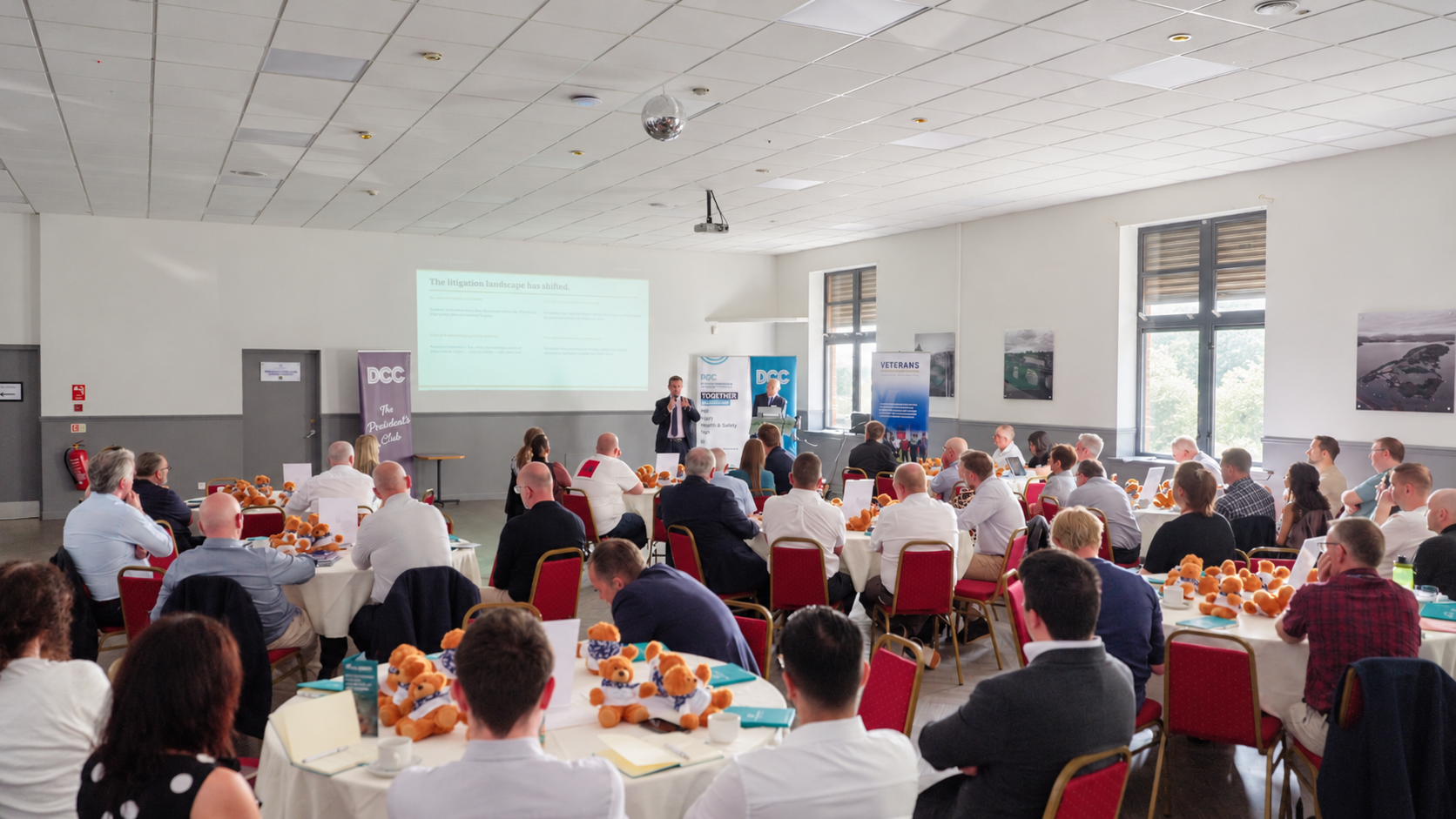 Delegates seated around tables listening to a seminar speaker at Dumbarton FC